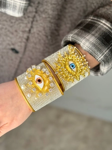 Detalle de un brazalete de oro con pedrería brillante y diseño de ojo turco de estilo retro