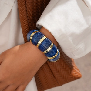 Close-up of deep blue acrylic chunky bracelet with gold metal rings and glitter texture