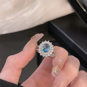 Detailed view of an oval blue gemstone ring with sparkling crystal accents in a hand