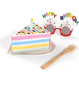 Rainbow striped triangle cake slice gift box with paper candle and bamboo fork on pink plate