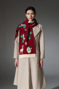 Close-up of red Christmas knit scarf with white reindeer, snowflakes and Santa patterns