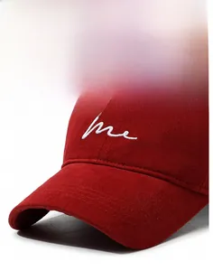 Detailed close-up of dark red baseball cap with white embroidered me logo on cotton fabric