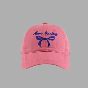 Close-up of pink cotton baseball cap featuring blue Moon landing embroidery and bow detail
