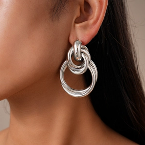 Close-up of a model wearing silver metallic geometric interlocking knot earrings