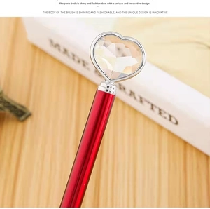 Macro shot of red metal pen featuring a faceted heart-shaped crystal on the silver cap