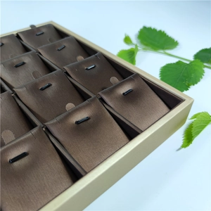Detail of 24-slot champagne gold jewelry display tray with chocolate brown velvet lining