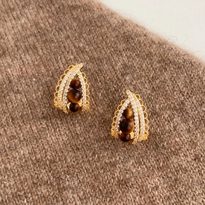 Orecchini a goccia in oro con pietre occhio di tigre e zirconi su maglione lavorato