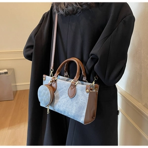 Détail du sac cabas en denim contrasté avec bordure en cuir et porte-monnaie rond