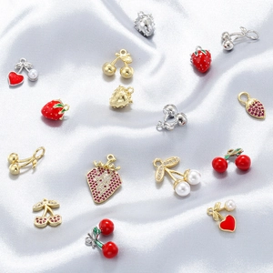 Detailed close-up of cherry and strawberry enamel charms with pearls on silver silk