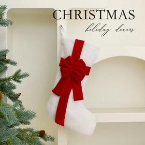 White plush Christmas stocking with red velvet bow hung by festive pine branches