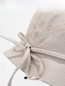 Close-up of beige sun hat fabric texture and stylish bow tie detail for women