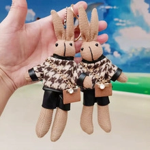 Close-up of cute plush bunny keychains wearing houndstooth sweaters and small backpacks
