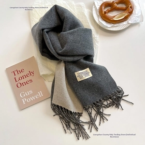 Detail of double-sided cashmere scarf in dark and light grey with tassel edges