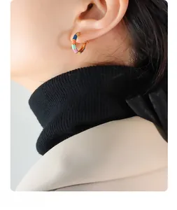 Détail de créoles en émail coloré portées par un mannequin en blazer beige chic