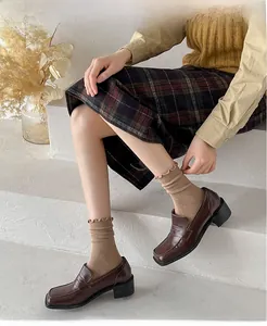Close-up of brown leather loafers with vintage square toe and stylish ruffled knit socks