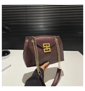 Detail showing deep burgundy crossbody bag with golden chain and geometric metal clasp