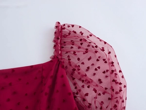 Détail de manches bouffantes en mesh rouge avec motifs de cœur sur robe en tulle