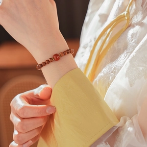 Close-up of beaded red agate and tiger eye stone bracelet on woman's wrist
