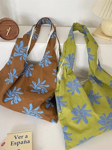 Artistic blue floral canvas tote bags in brown and green displayed in a cozy interior