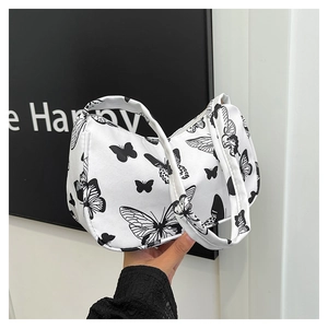 Close-up of black and white butterfly print on canvas underarm bag held by hand