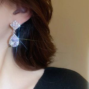 Macro detail of silver-tone drop earrings with sparkling zircon stones on model