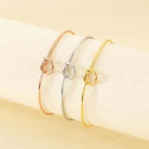 Set of three minimalist knotted open cuff bracelets in gold, silver, and rose gold finish