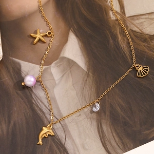 Detailed close-up of 18K gold-plated necklace with starfish, shell, and purple pearl charms