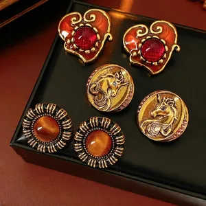 Vintage resin heart and unicorn earrings set with amber cat eye stones on black display