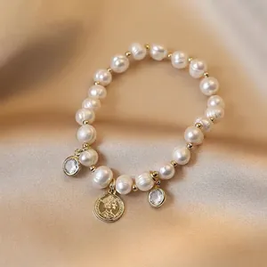 Baroque freshwater pearl bracelet with gold coin and zircon charms on champagne satin