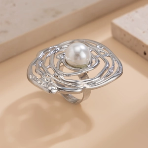 Close-up of irregular hollow silver ring featuring a round faux pearl on a textured stone
