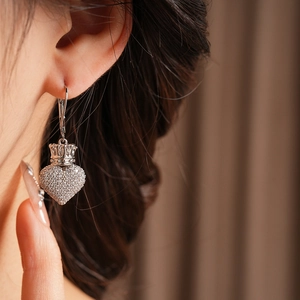 Vue macro d'une boucle d'oreille cœur et couronne en argent sertie de zircons brillants