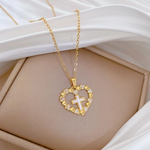 Detail of gold heart pendant with zircon stones and white mother-of-pearl cross on silk