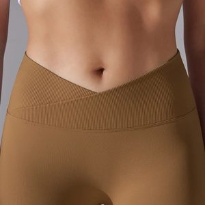 Detail view of V-shaped cross waistband on seamless ribbed yoga pants in caramel brown