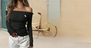 Detail of black off-the-shoulder knit sweater with horse embroidery and long sleeves