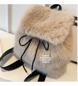 Detail view of beige faux fox fur backpack with black drawstring and metal cap accents