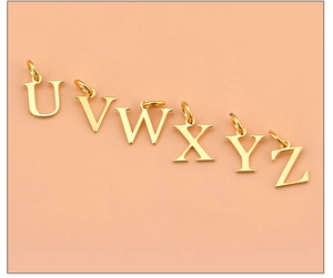 Detailed view of 925 silver gold-plated alphabet pendants U V W X Y Z on pink background