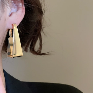 Close-up of model wearing gold geometric triangle earrings in a minimalist style