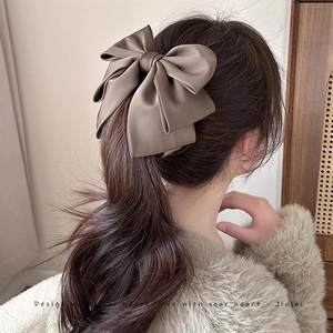 Latte brown satin bow banana clip shown on long hair from the back view