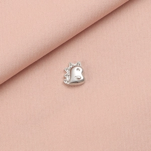 Detailed close-up of a silver stainless steel dinosaur pendant on pink fabric