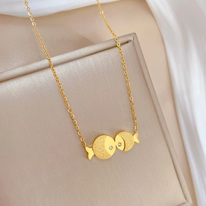 Macro detail of gold kissing fish pendant with matte finish and tiny crystal eye