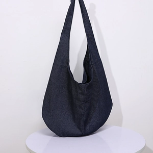 Bolso de hombro hobo retro de lona de algodón azul oscuro en una mesa blanca