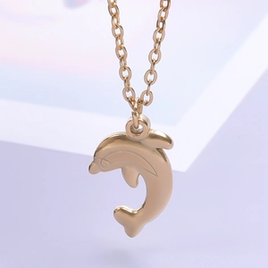 Macro detail of jumping dolphin pendant in polished gold finish with classic O-chain