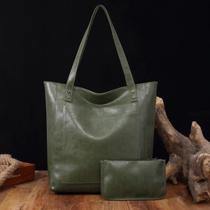 Sac cabas vintage en cuir ciré vert avec pochette assortie sur fond bois rustique