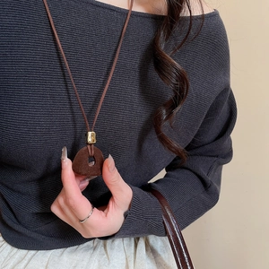 Close-up of a vintage dark brown flocked resin pendant on a long sweater necklace