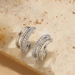 Macro shot of layered silver ear hoops with polished, beaded, and cubic zirconia bands