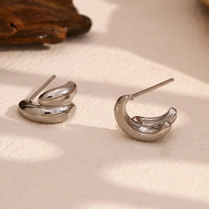 Macro detail of silver-tone irregular curved double-layer earrings with polished finish