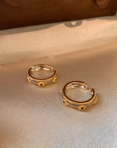Macro detail of vintage gold and silver rings with green gemstones and woven texture