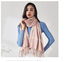Détail de l'écharpe d'hiver à carreaux roses avec rayures beige et pompons doux