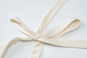 Detail of the chic cream-colored halter neck tie with a soft bow on the summer knit dress