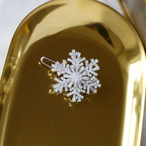 Macro shot of silver rotating snowflake brooch with zircon on a luxury golden tray